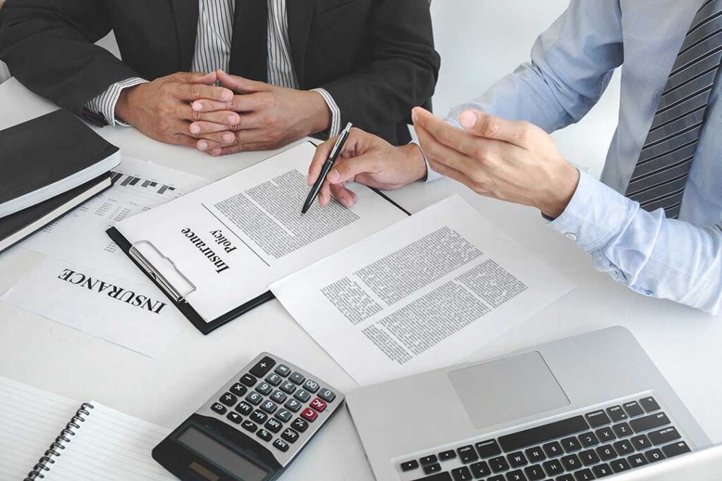 A family looking over household bills and documents together at a kitchen table.