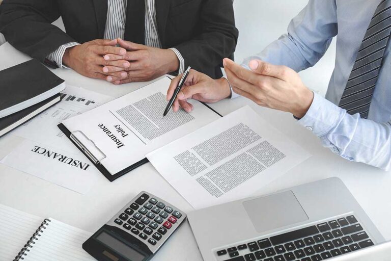 A family looking over household bills and documents together at a kitchen table.